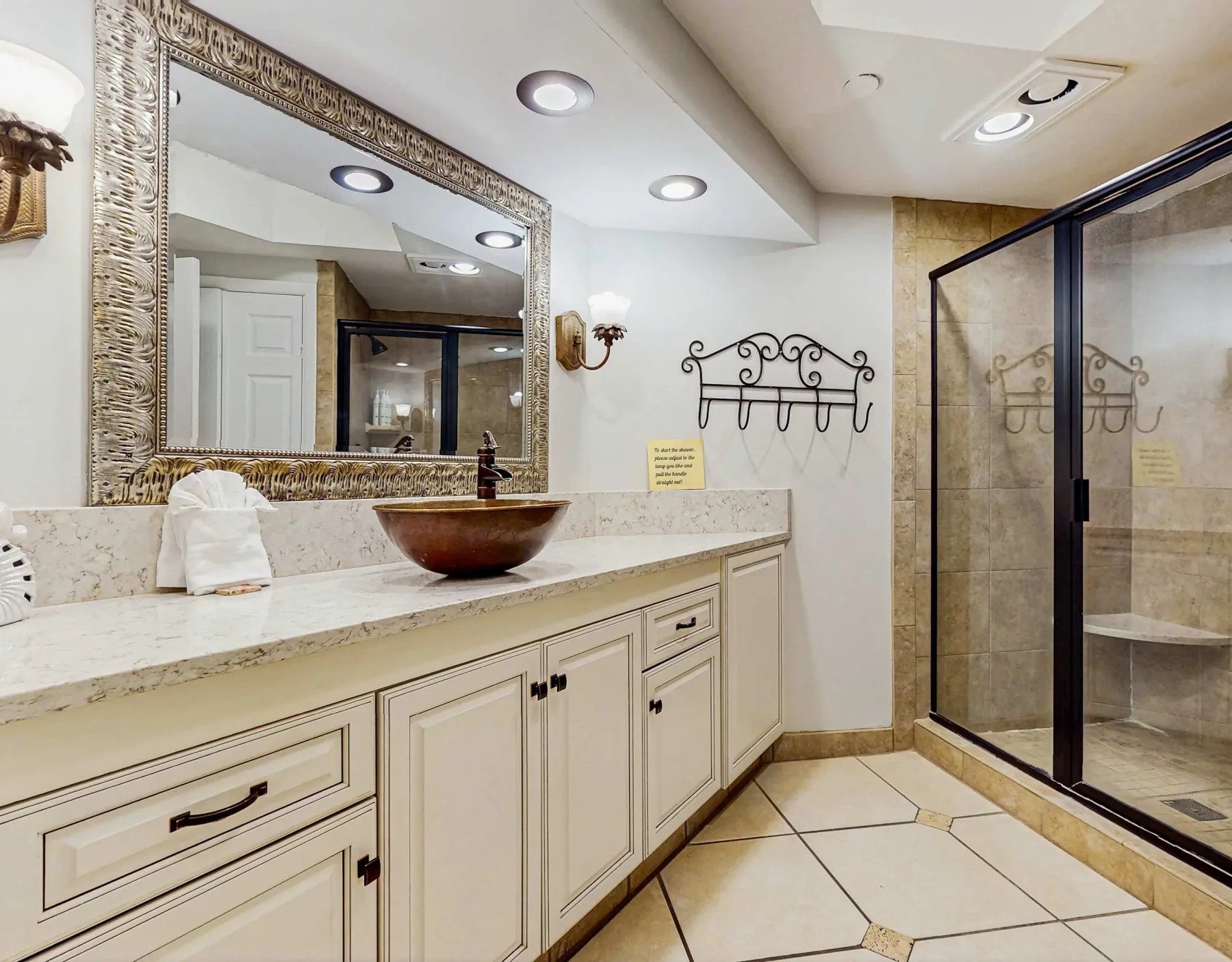 A bright bathroom with a long vanity, vessel sink, and glass shower.