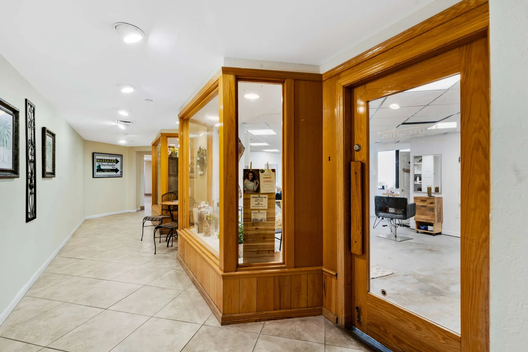 Shared amenity: A tiled hallway with wood-framed glass partitions and framed pictures on the wall.