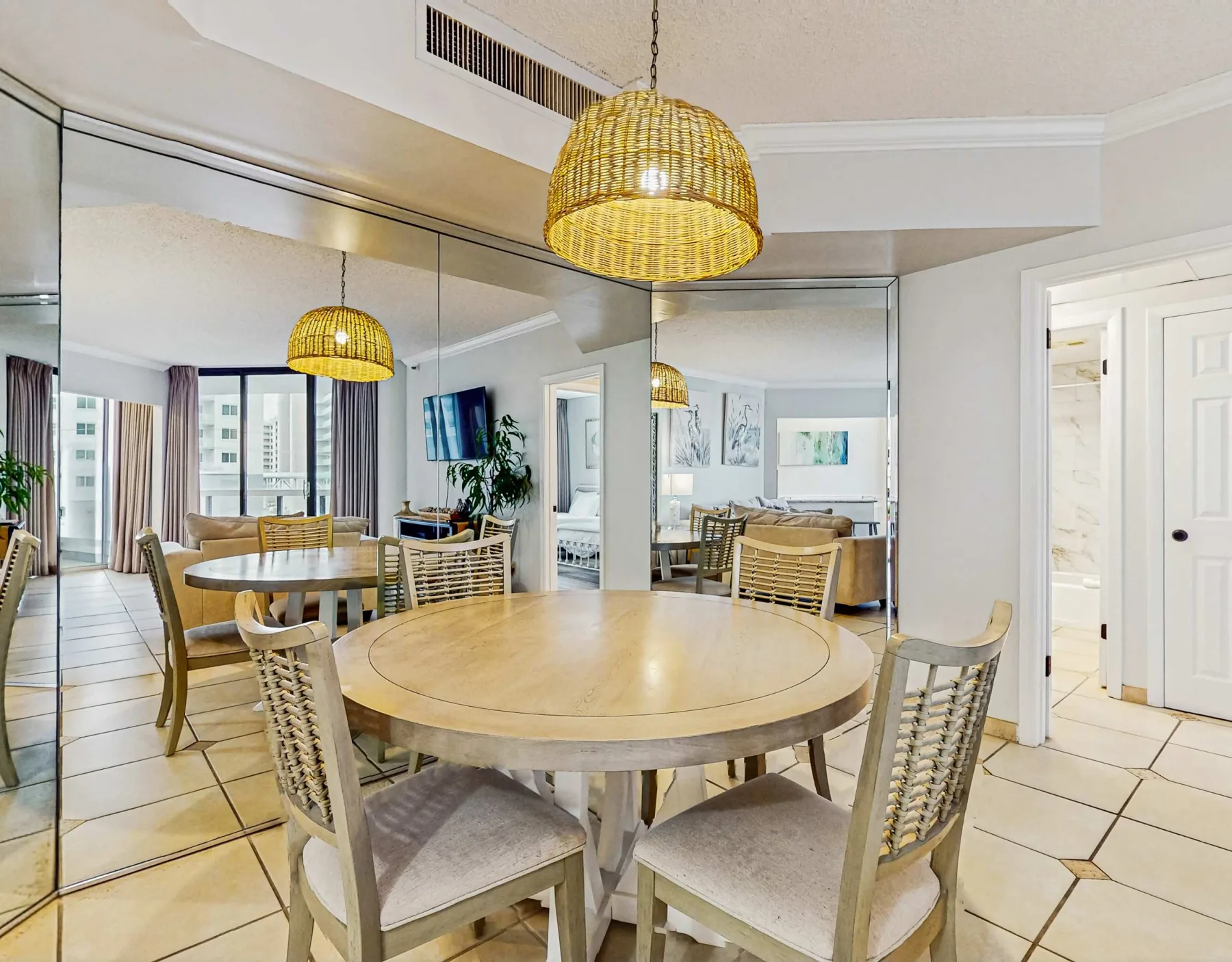 A dining area with a round wooden table and woven pendant light.