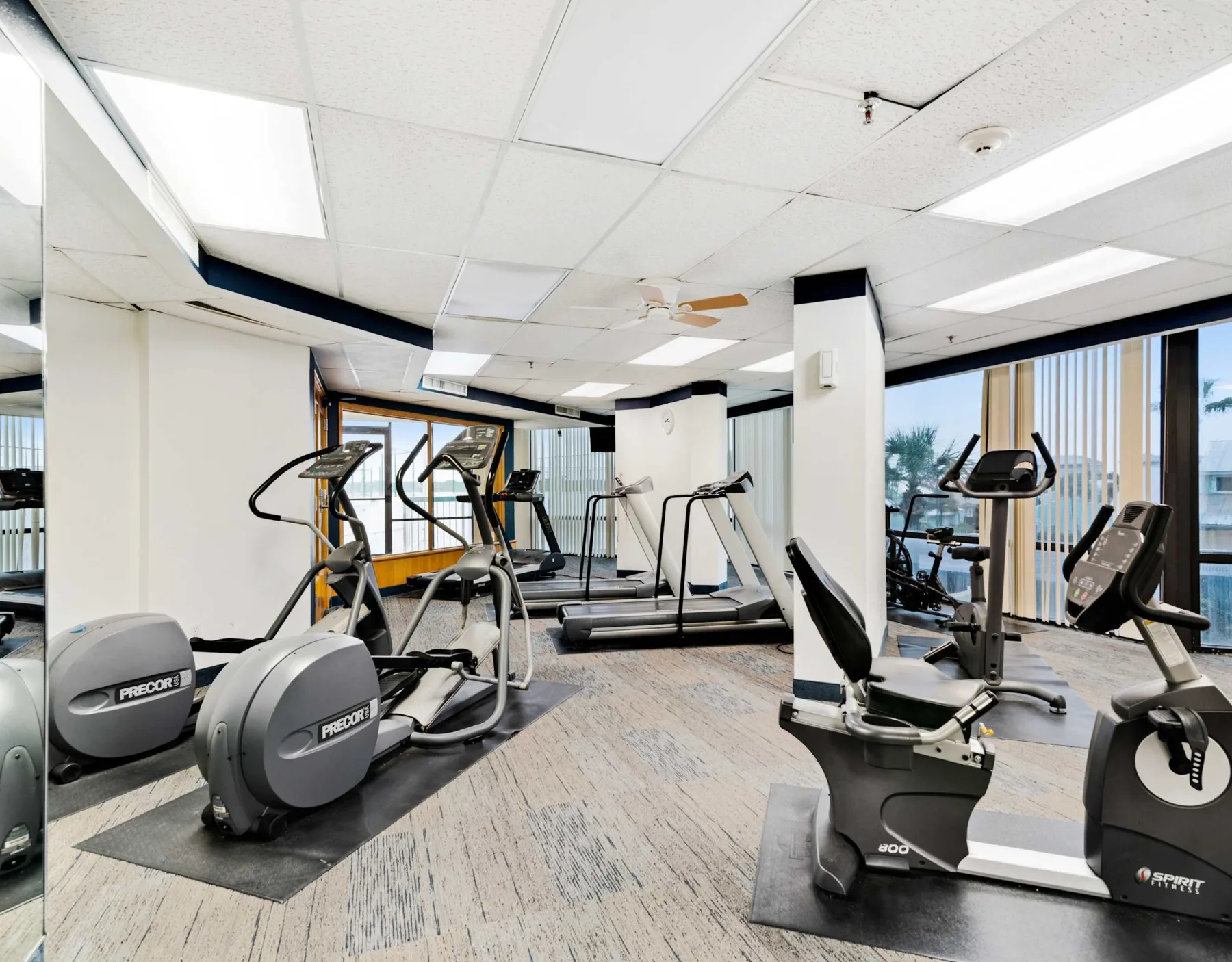 Shared amenity: Fitness room with exercise machines beside large windows.