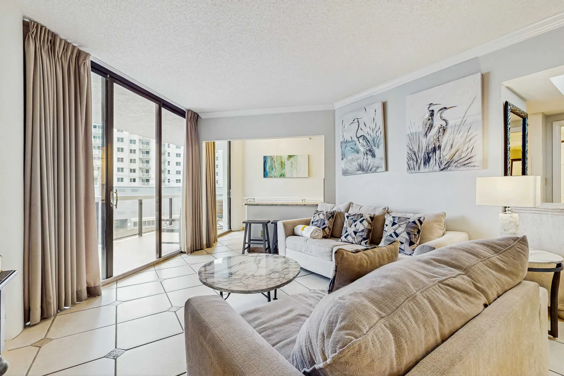 A bright living room with seating beside large glass doors and framed artwork.
