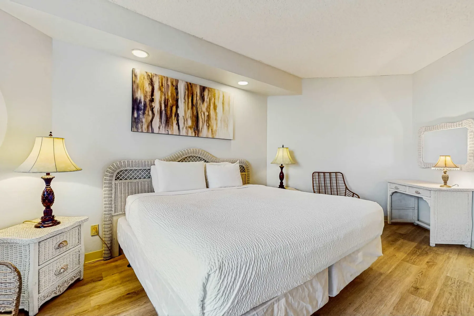 A bedroom with a large bed, bedside tables, and abstract wall art.