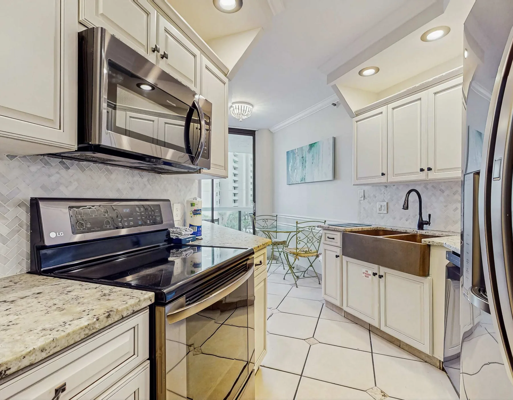 A bright kitchen with white cabinetry, stone counters, and a dining nook.