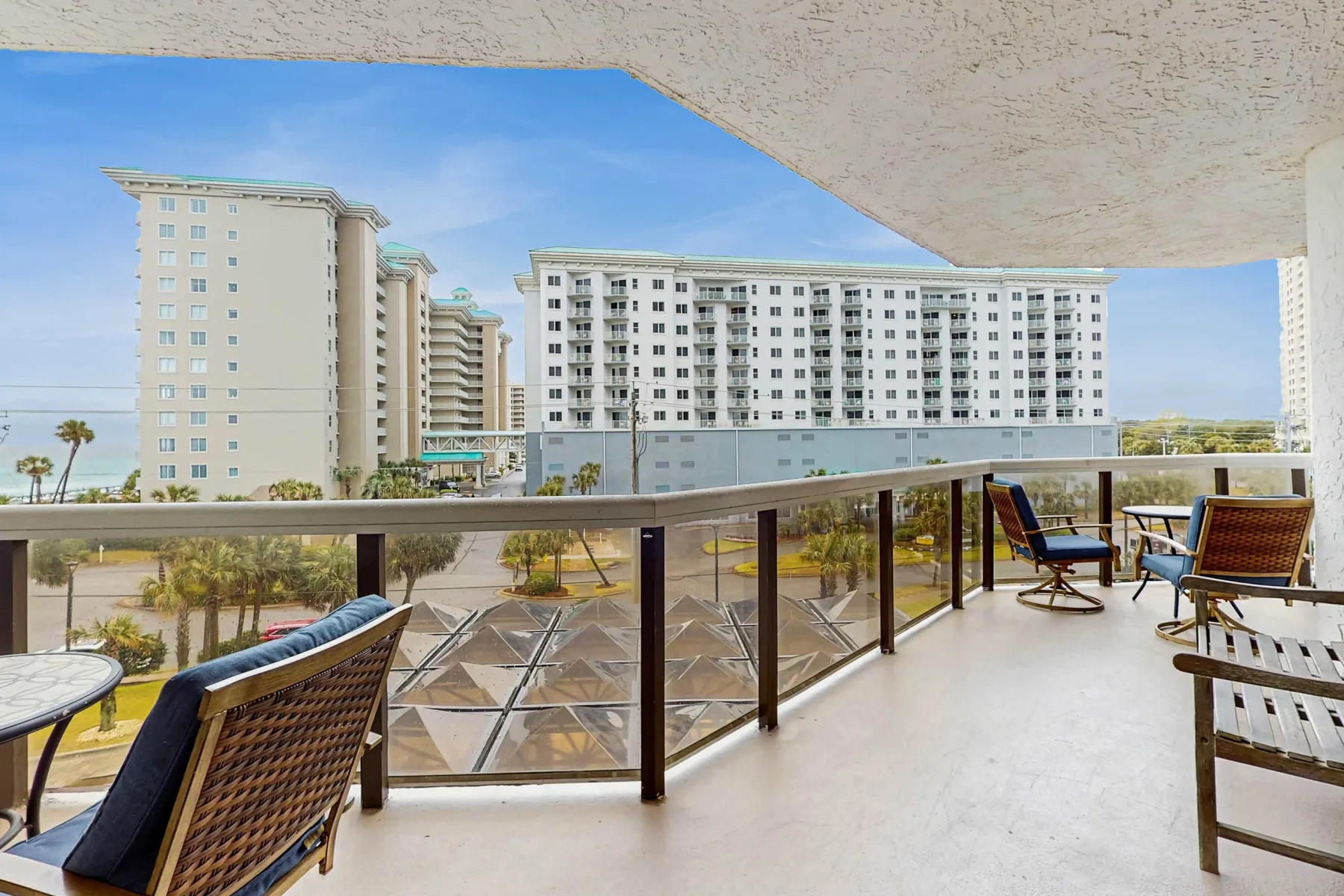 A balcony seating area overlooks landscaped grounds and nearby high-rise buildings.