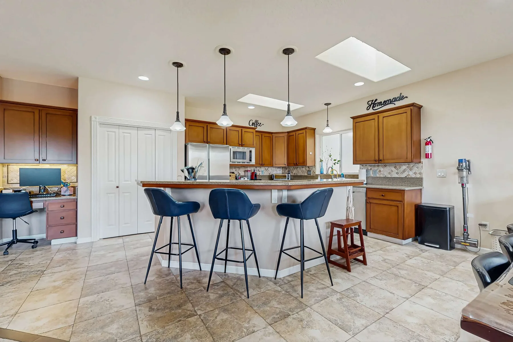 Una cocina luminosa tiene una isla central con asientos de barra y gabinetes de madera.