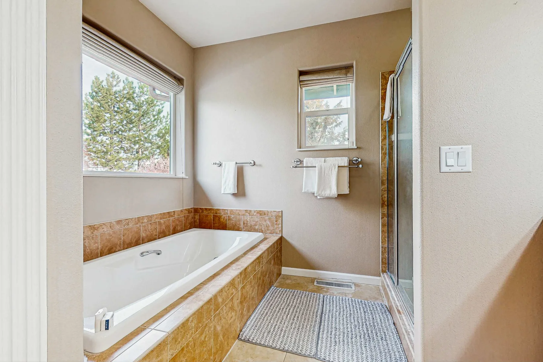 Un baño con bañera empotrada, ventanas y una ducha de vidrio.