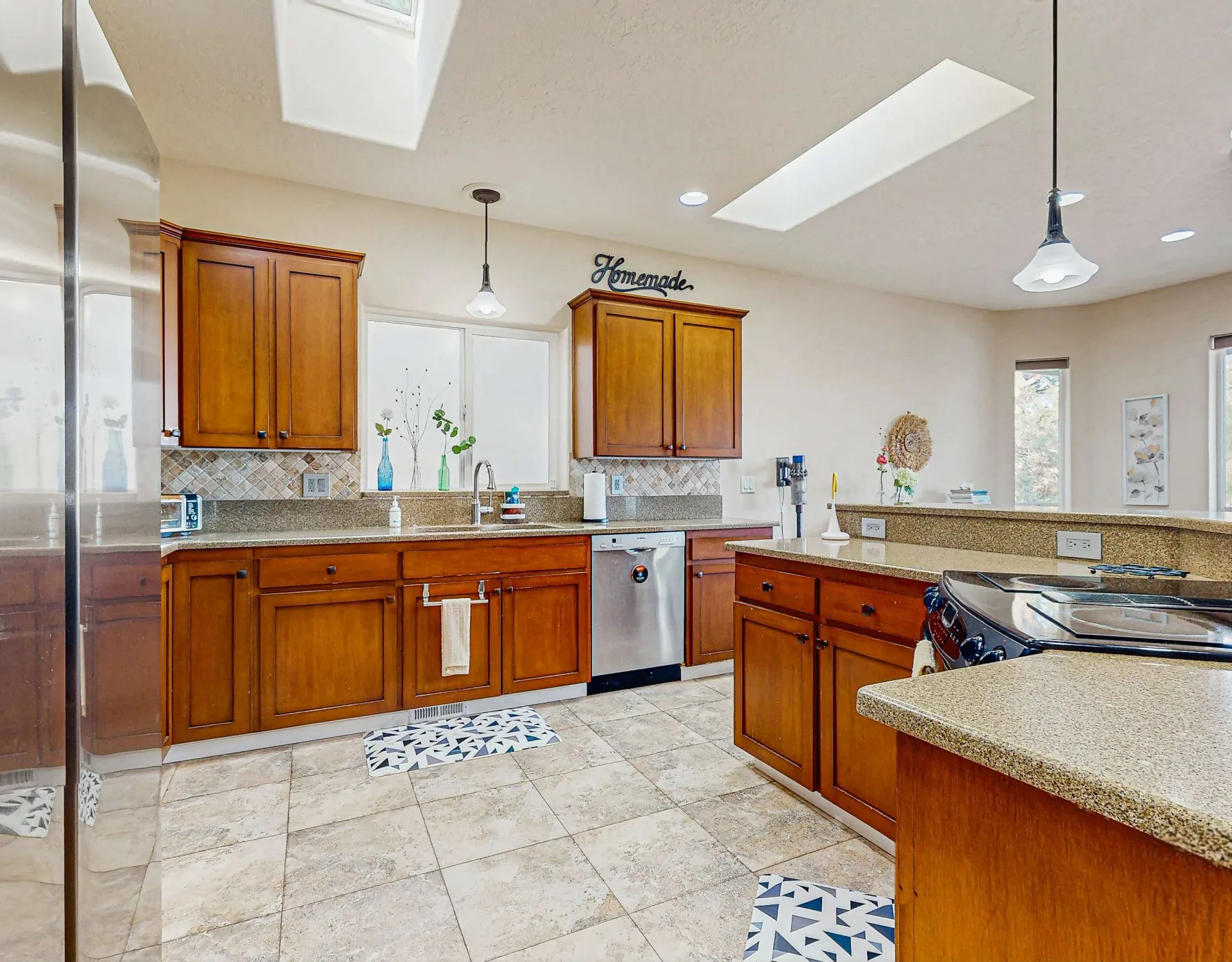 Una cocina con gabinetes de madera, piso de baldosas e isla central.