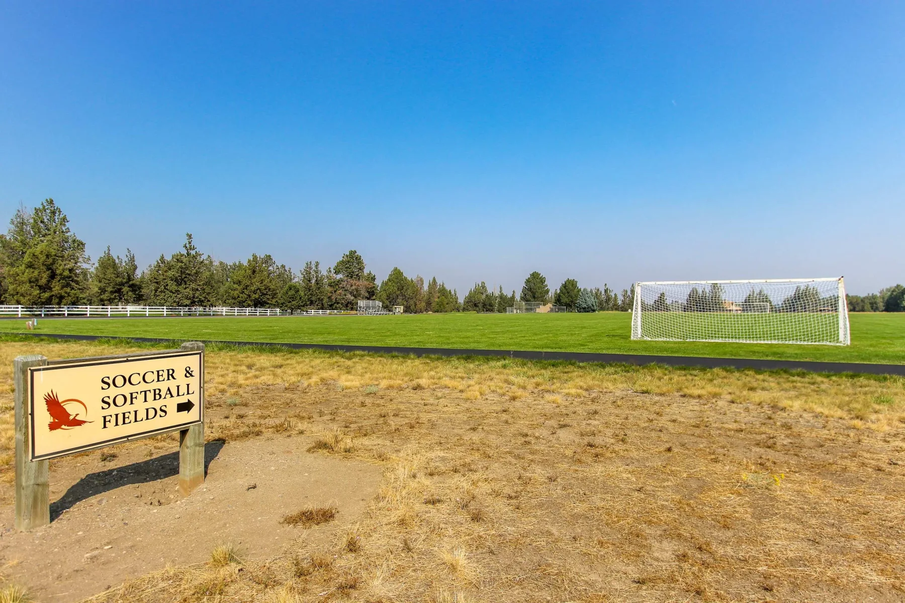 Zona común: Un campo de fútbol y sóftbol con una portería y un letrero junto al terreno seco.