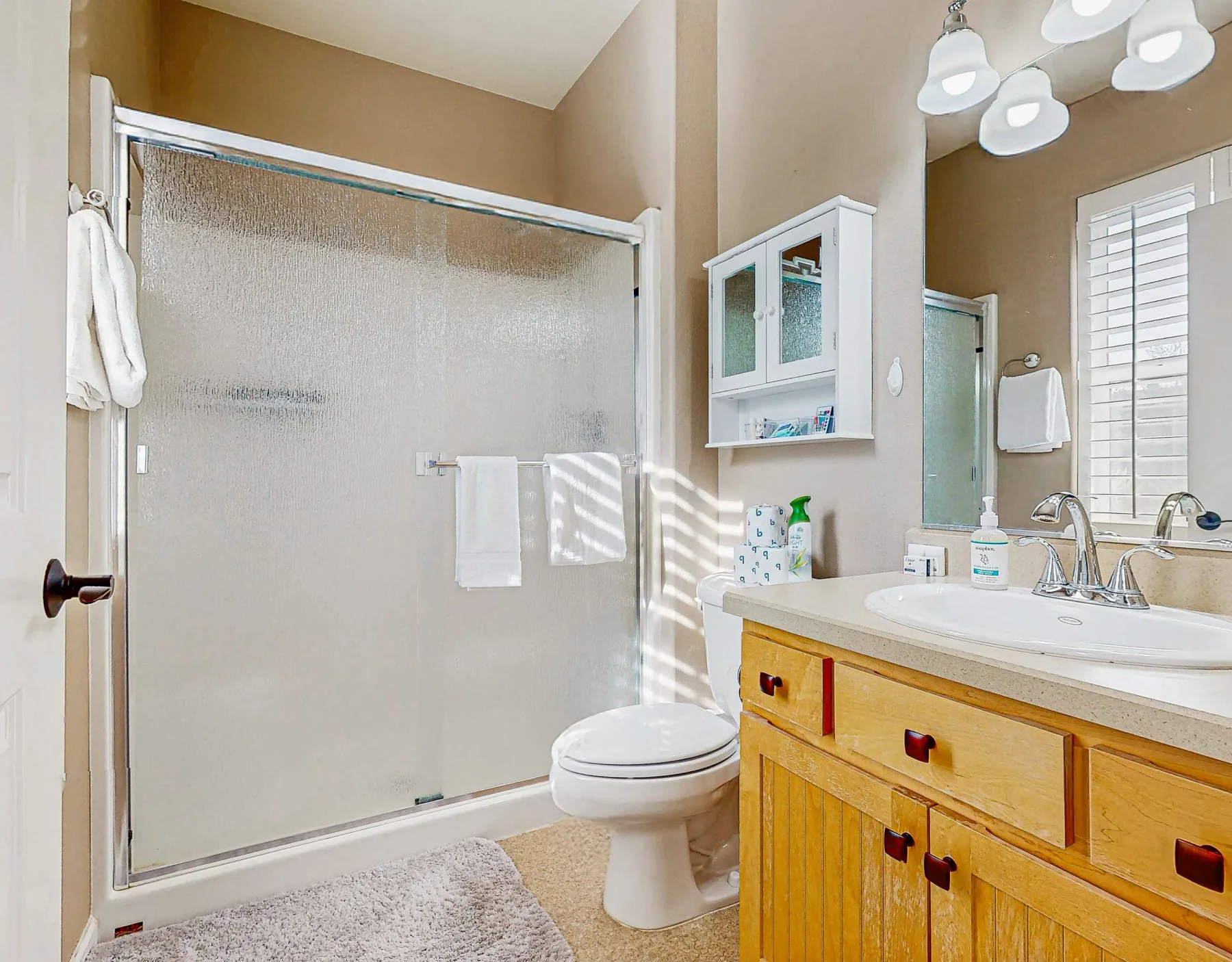 Un baño con ducha de vidrio, inodoro y mueble de madera.