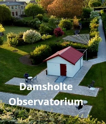 Representative hotel space: A small white outbuilding with a red roof sits beside a paved walkway in a landscaped garden.