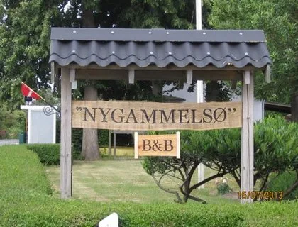 Representative hotel space: A wooden roadside sign stands in a grassy garden beneath a small roof.