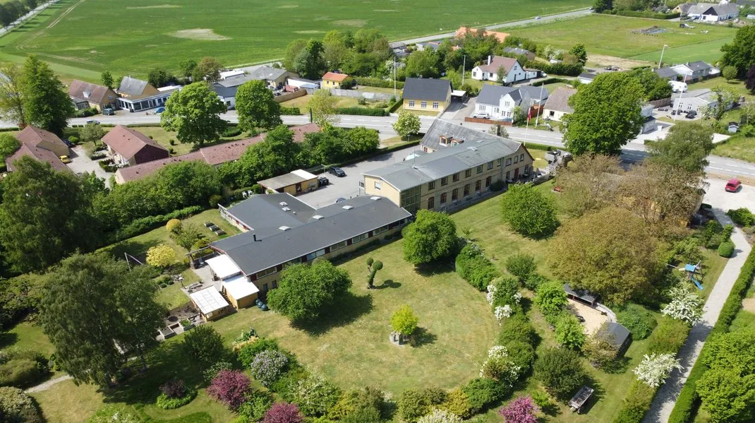 Representative hotel space: Aerial view of a large building surrounded by lawns, trees, and nearby homes.