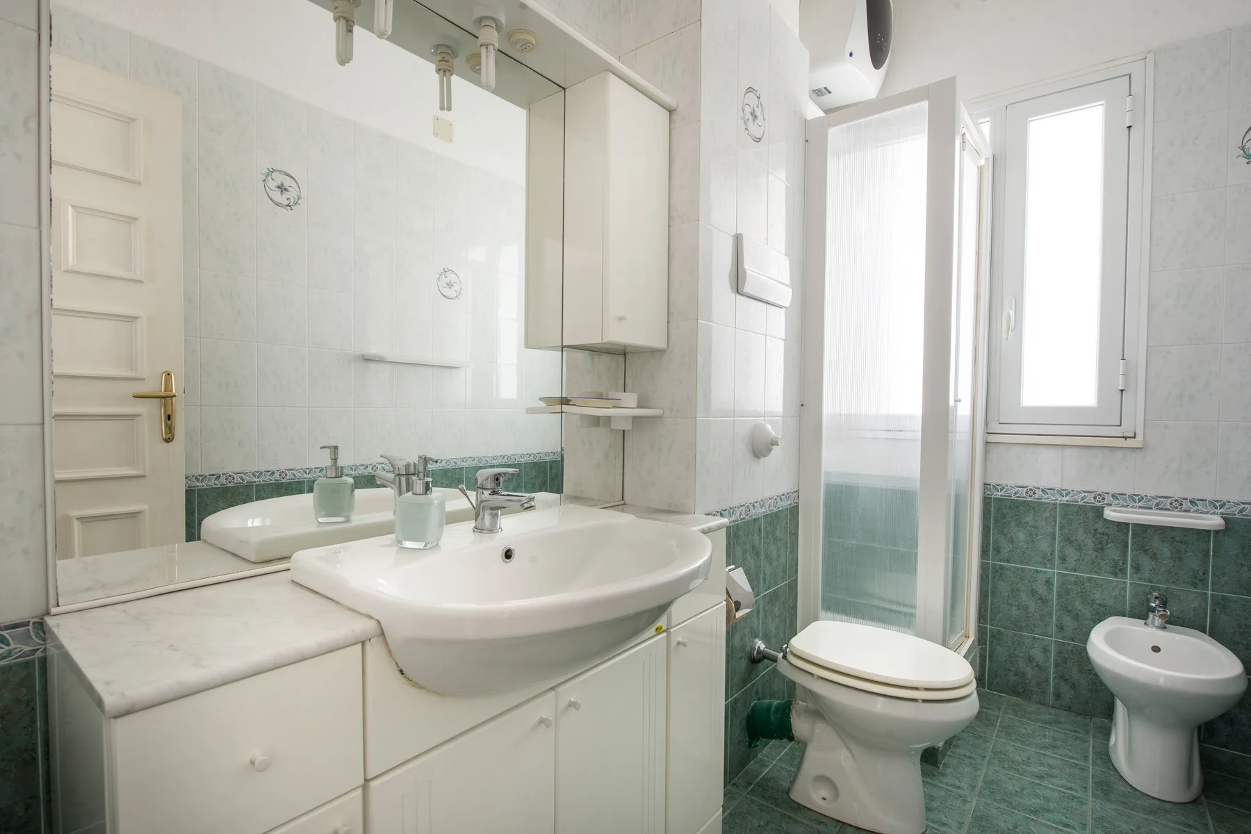 A tiled bathroom with a sink, toilet, and bidet.