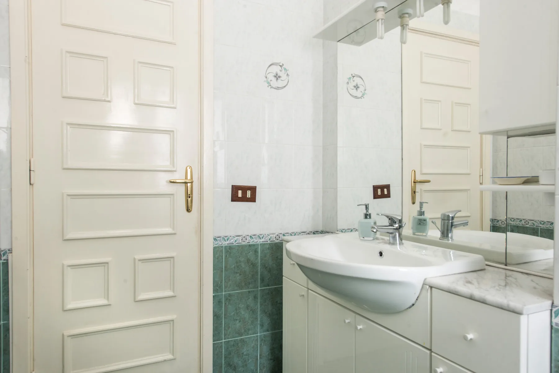 A bathroom with a sink, mirror, and white paneled door.