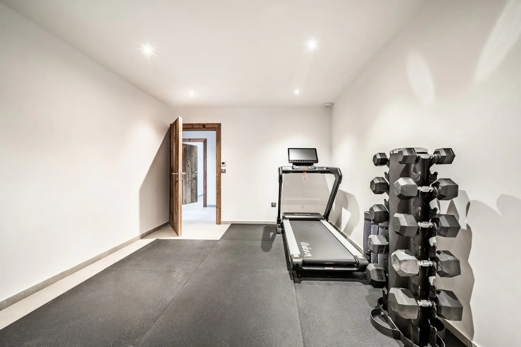 Un gimnasio con una cinta de correr y un soporte para pesas.
