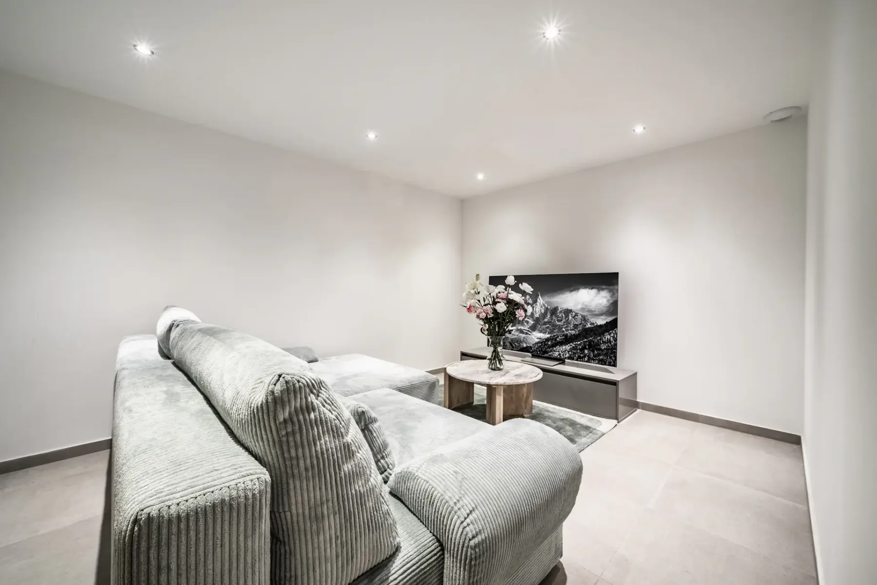 Una sala de estar con asientos, un televisor y una mesa de centro.