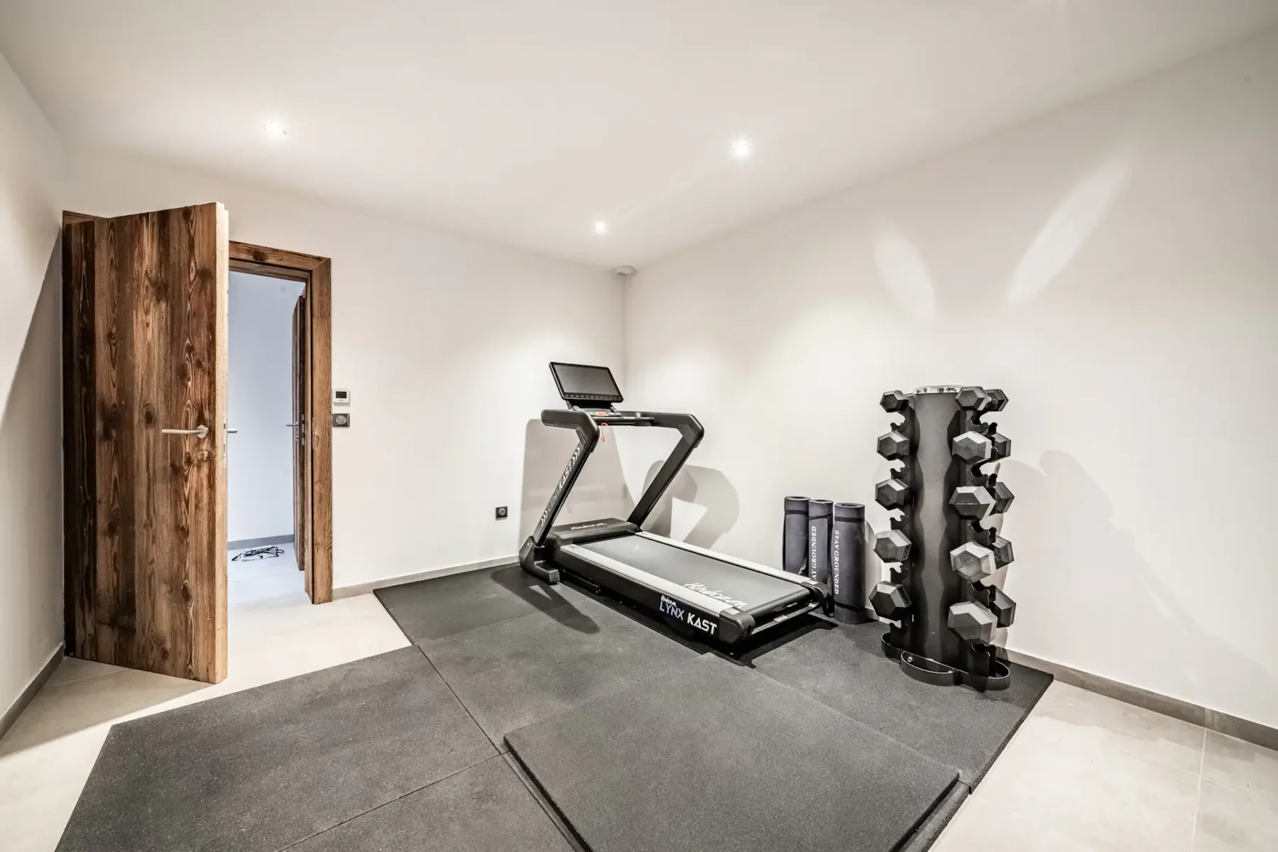 Un gimnasio en casa con una cinta de correr y un soporte para pesas.