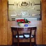 Espacio representativo del hotel: Un mostrador de recepción de hotel con flores y un panel decorativo de vidrio.