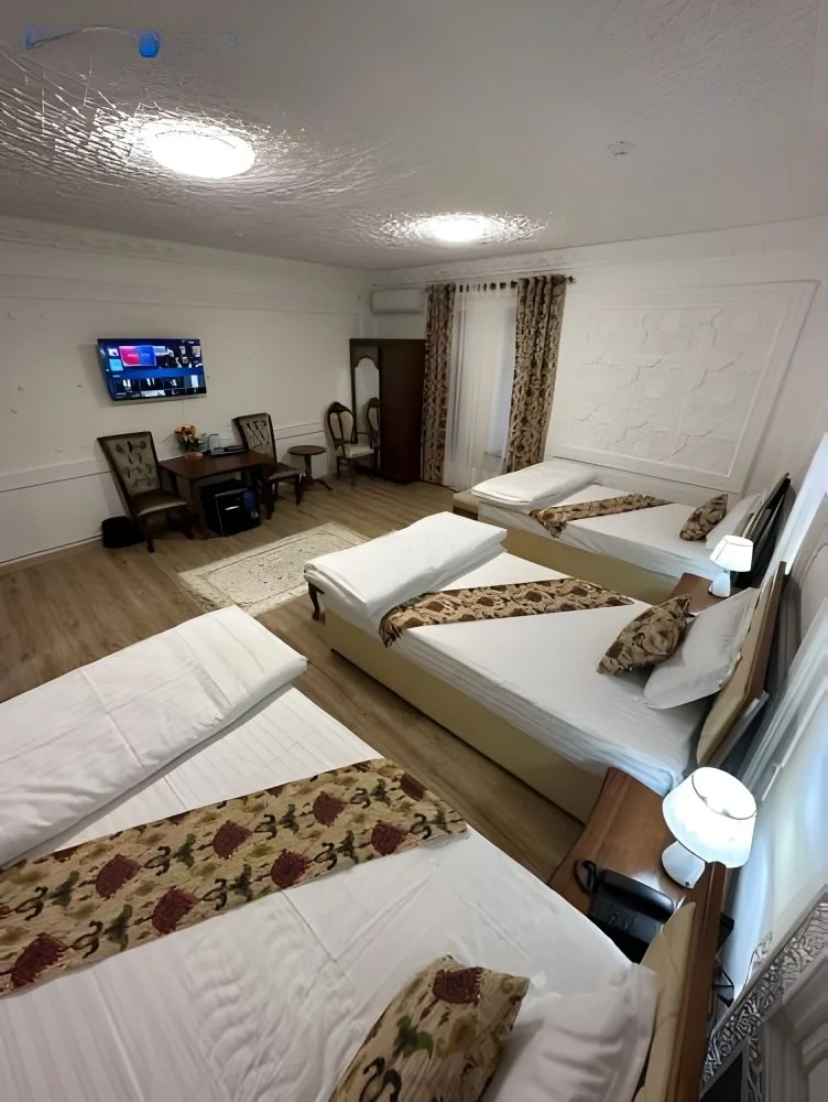 Espacio representativo del hotel: Un dormitorio con varias camas, caminos de cama estampados y una pequeña zona de estar.