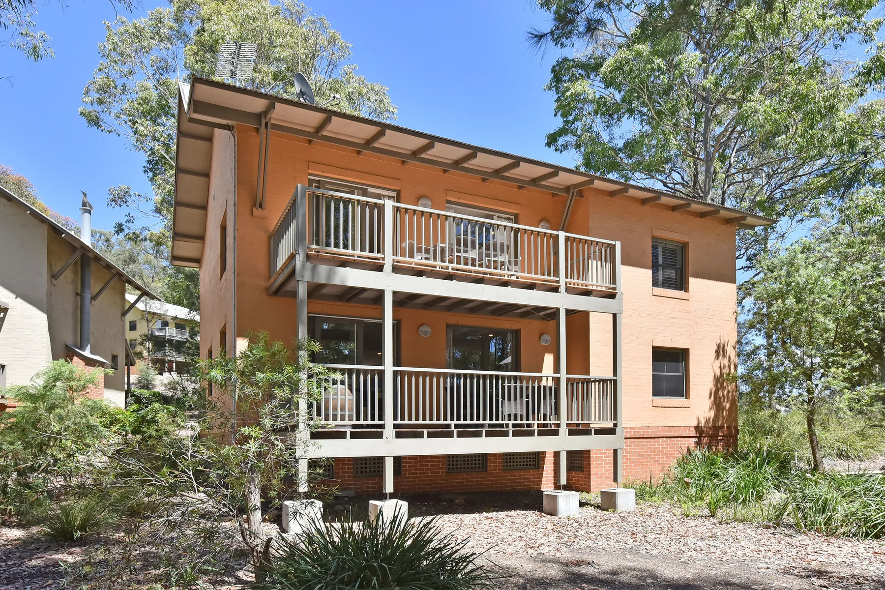 Shared amenity: A two-story orange building with balconies surrounded by trees and shrubs.