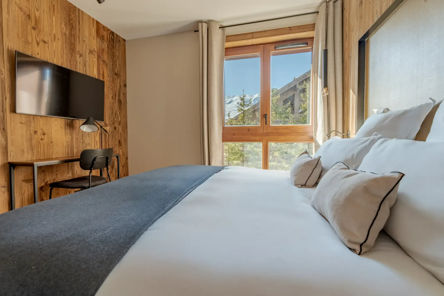 Un dormitorio con una cama bien tendida junto a una ventana grande.