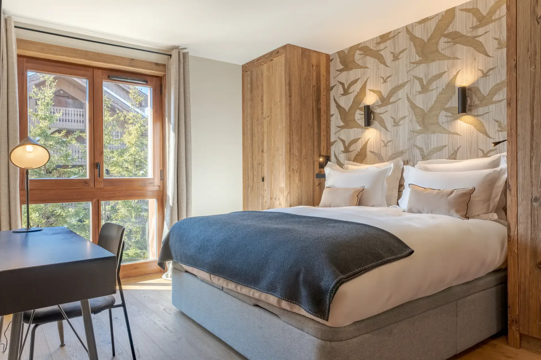 Un dormitorio con una cama doble, papel tapiz estampado y una ventana grande.