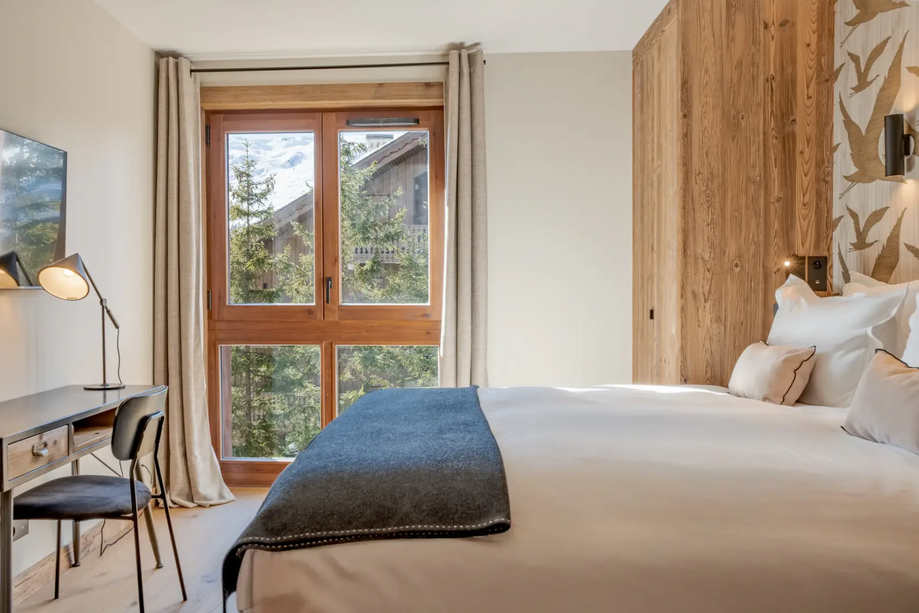 Un dormitorio con una cama junto a una pared revestida de madera y una ventana amplia.