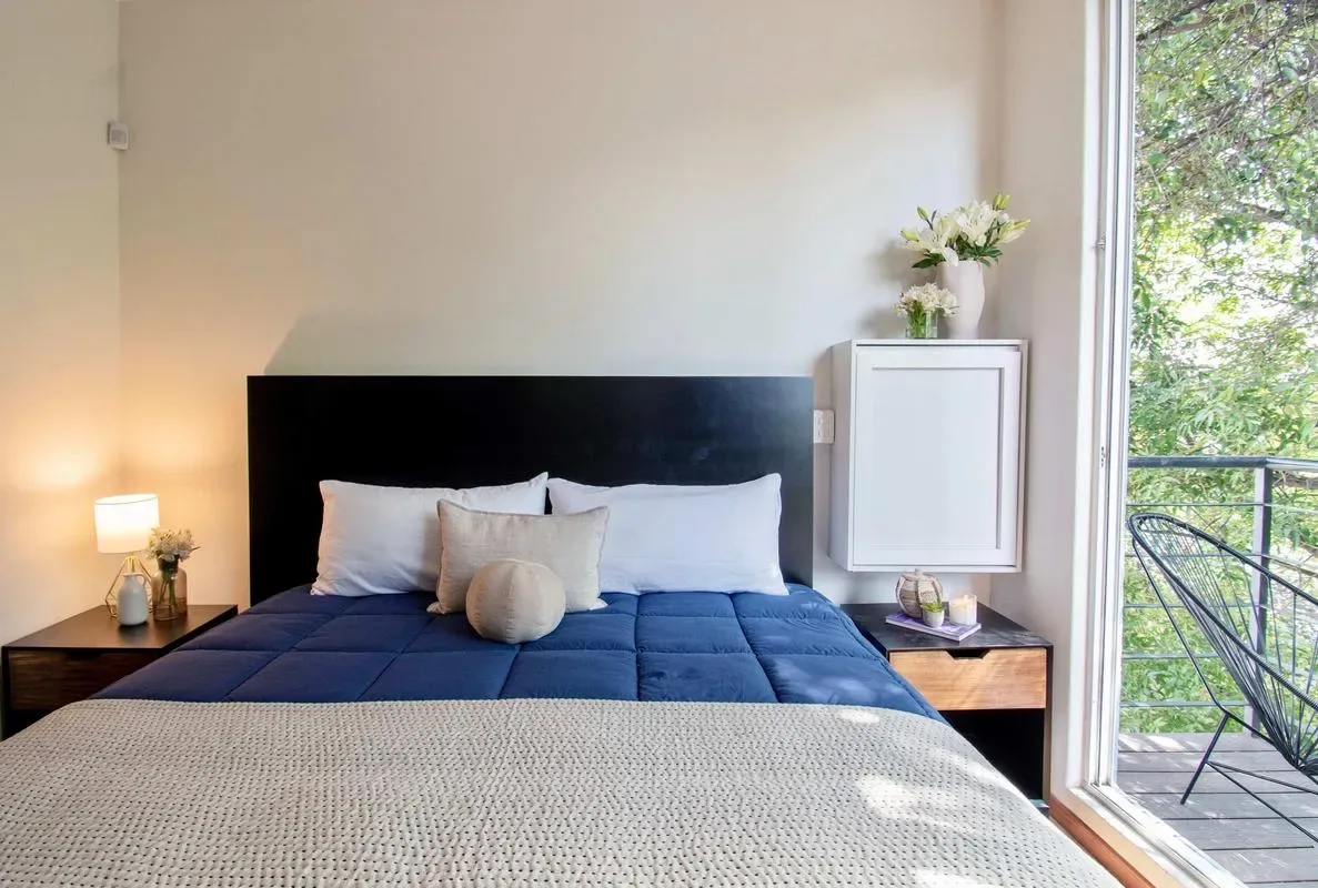 A bedroom with a large bed beside a window overlooking greenery.