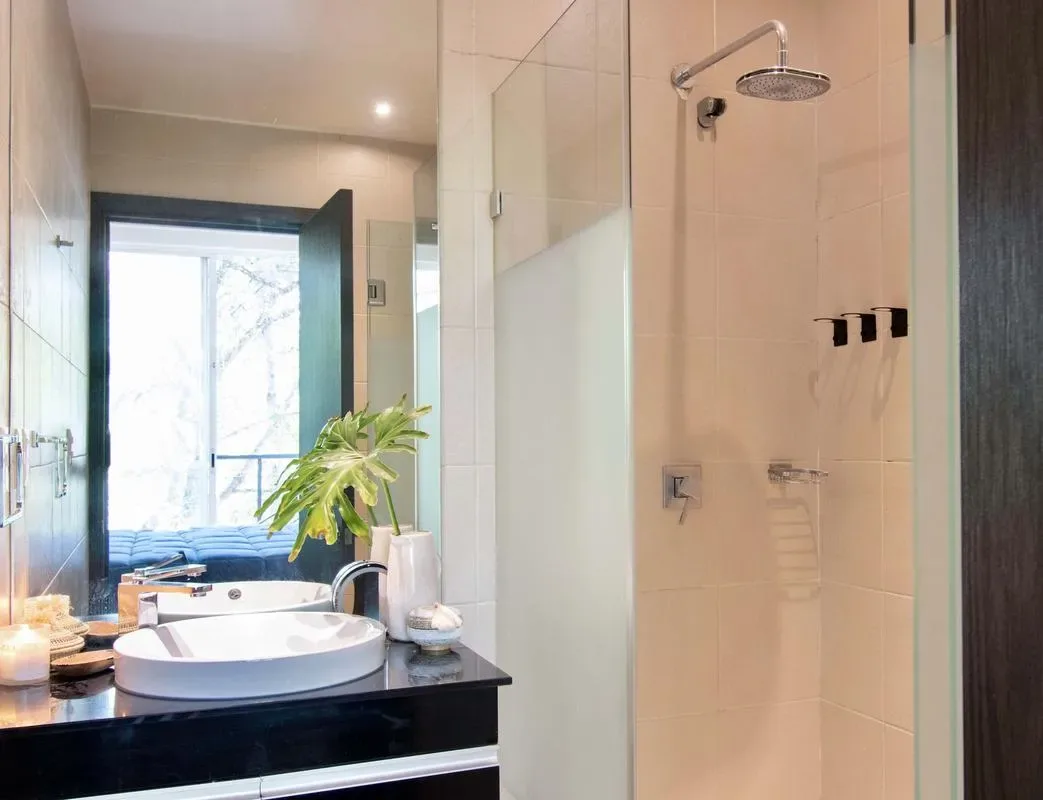 A bathroom vanity with a round basin beside a glass shower.