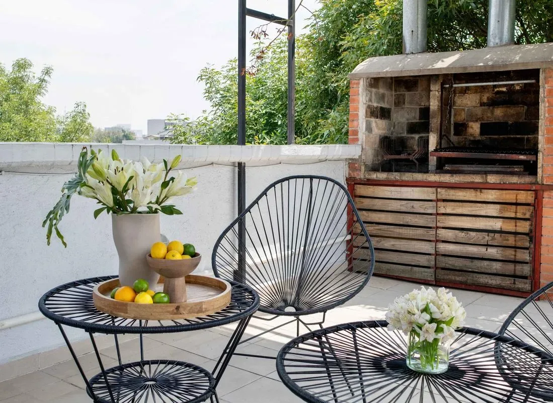 Shared amenity: A rooftop terrace with wire seating, fruit, flowers, and a built-in grill.