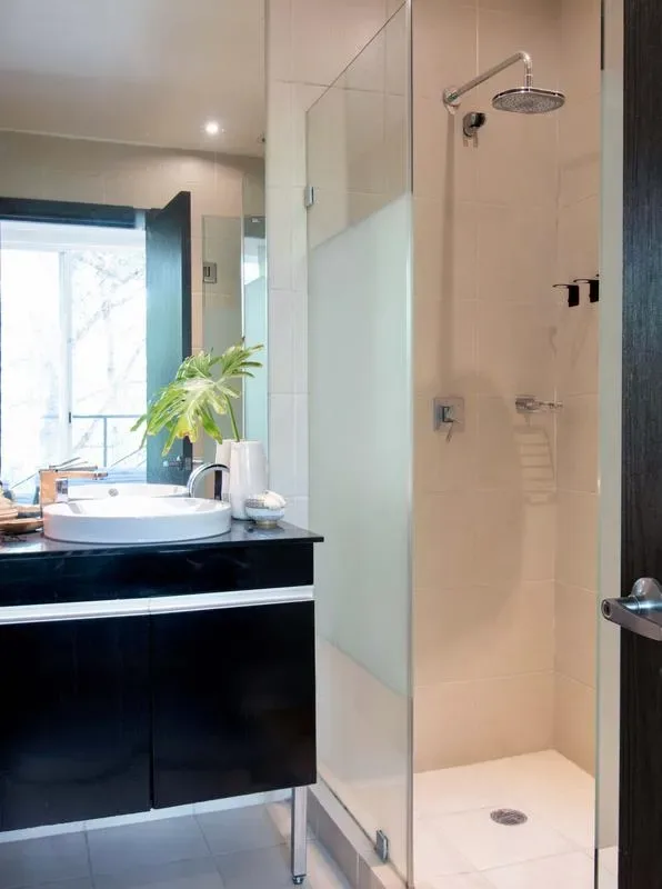 A bathroom vanity with a sink stands beside a tiled shower.