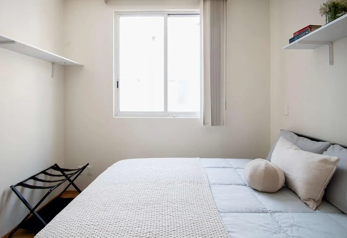 A bedroom with a bed beneath a bright window.