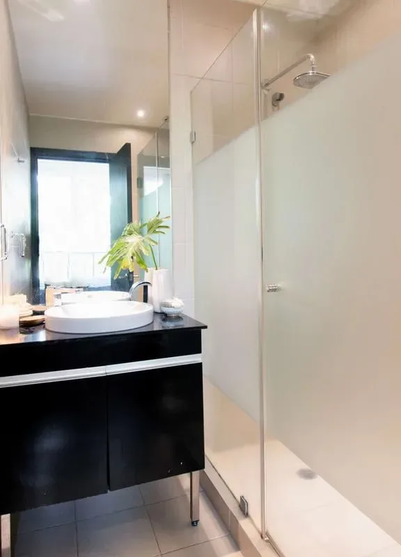 A modern bathroom with a vanity and glass-enclosed shower.