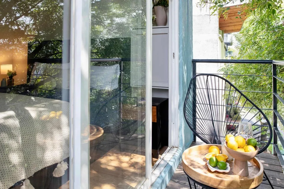 A small balcony seating area with a round table and leafy views.
