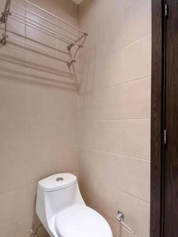 A tiled bathroom with a toilet and a metal towel rack.