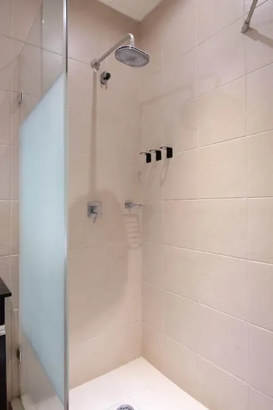 A tiled shower area with a wall-mounted showerhead and glass panel.