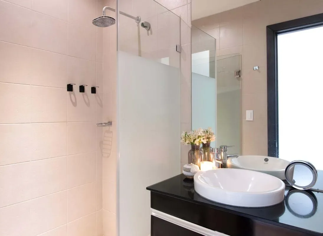 A modern bathroom with a glass shower and a vessel sink on a dark vanity.