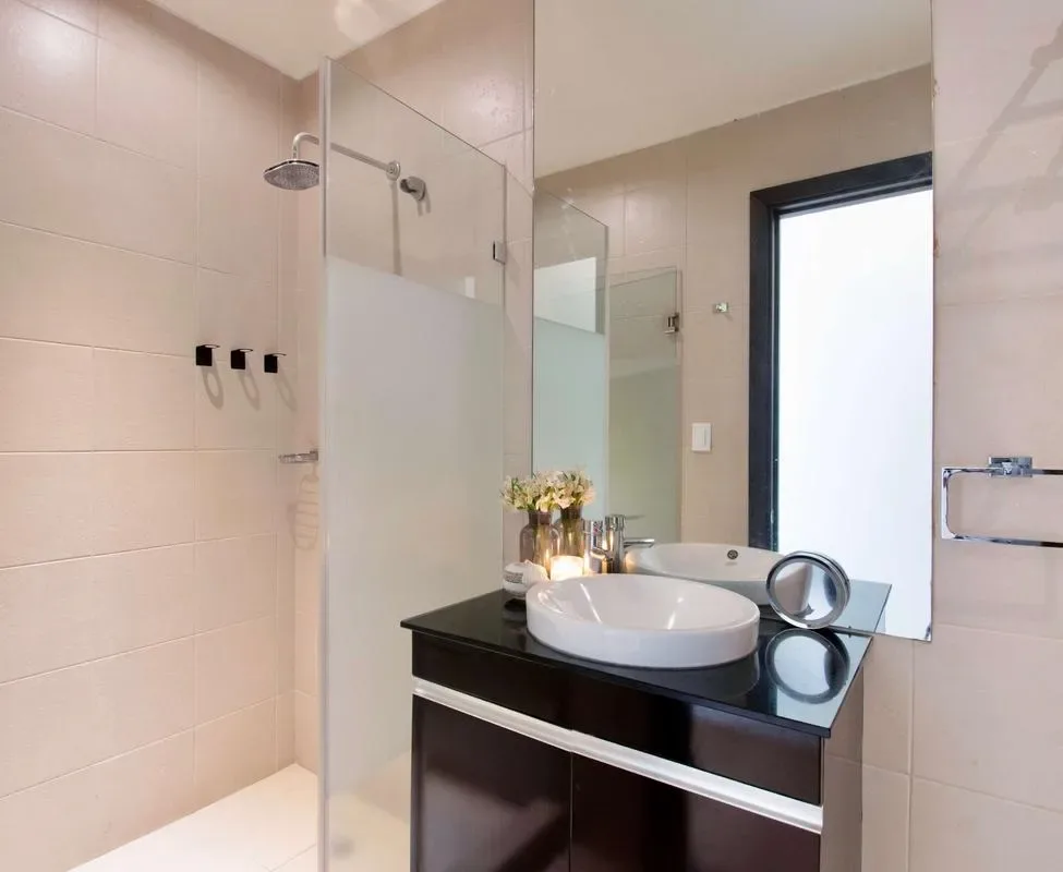 A modern bathroom with a glass shower and a dark vanity.