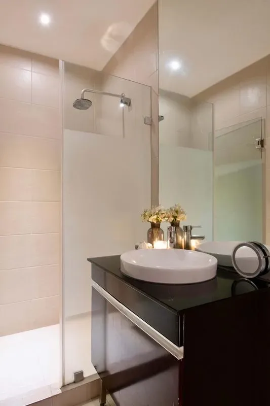 A bathroom with a glass shower and a dark vanity topped by a basin.