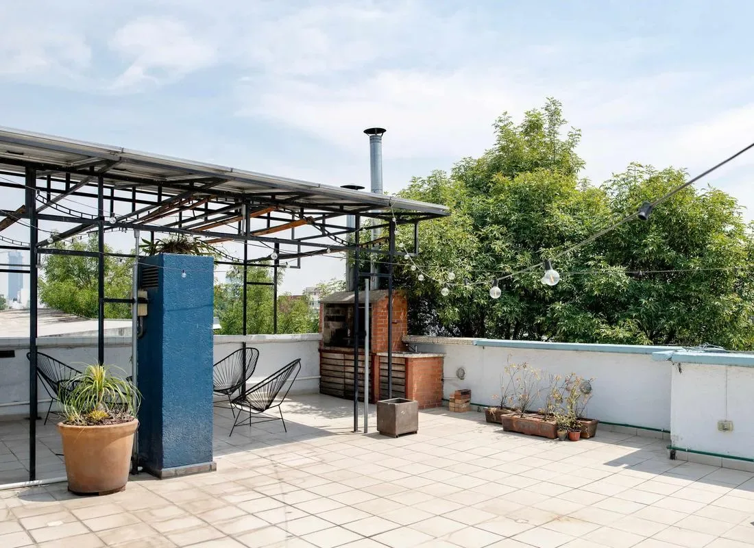 Shared amenity: A rooftop terrace with tiled flooring, seating, and potted plants.