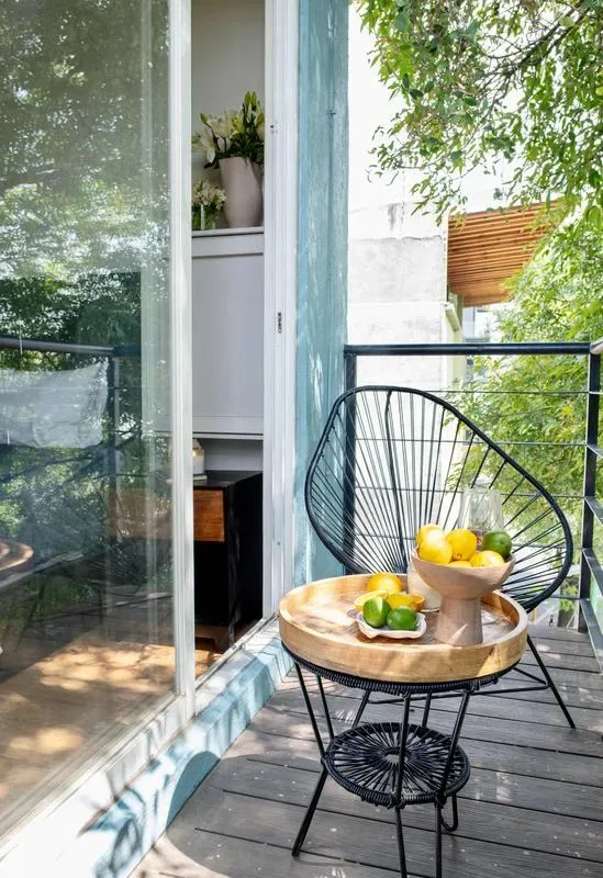A small outdoor seating area has a round table with a bowl of fruit.