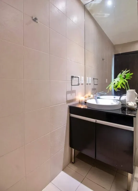 A tiled bathroom with a sink and dark vanity.