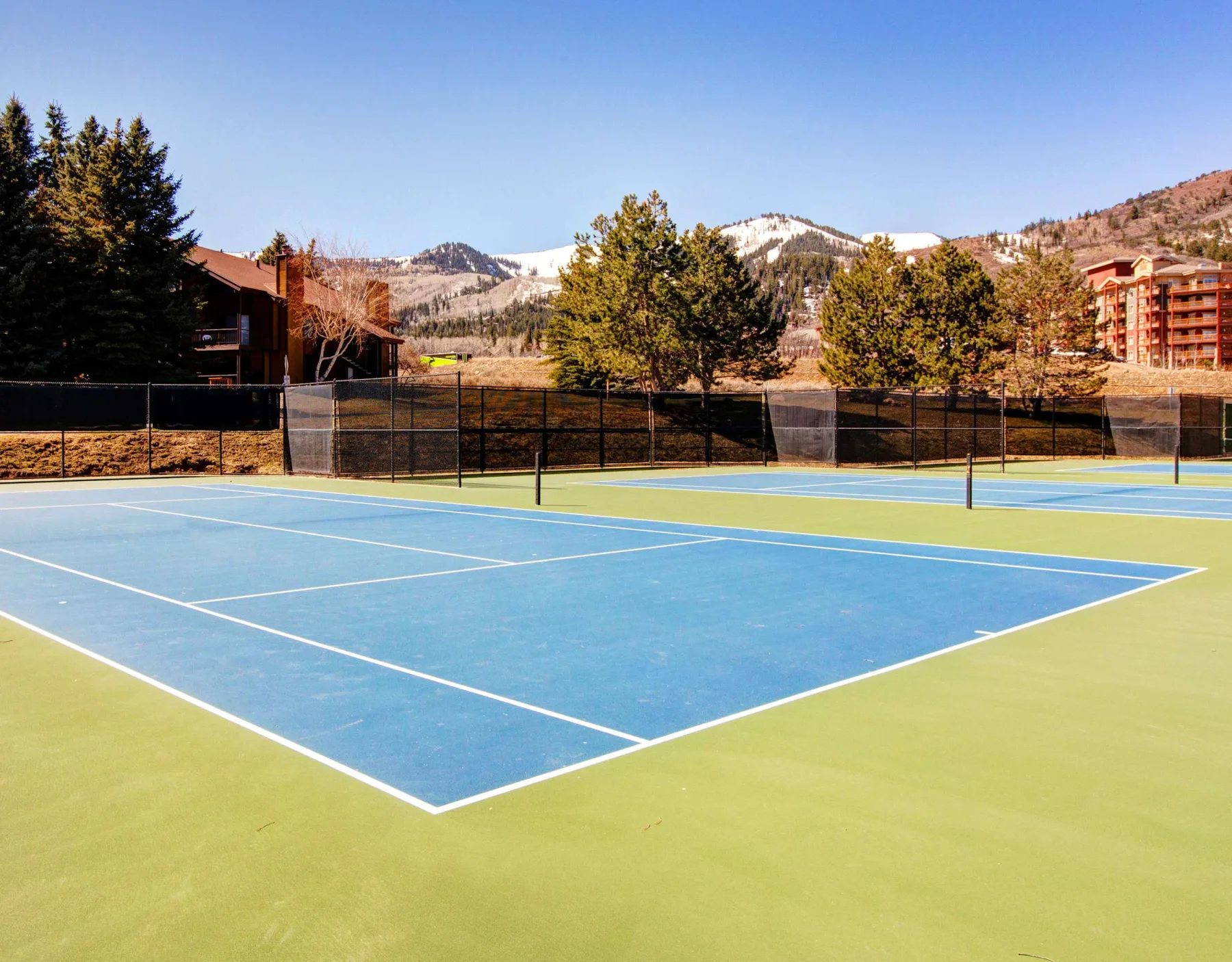 Zona común: Cancha de tenis al aire libre con montañas al fondo.