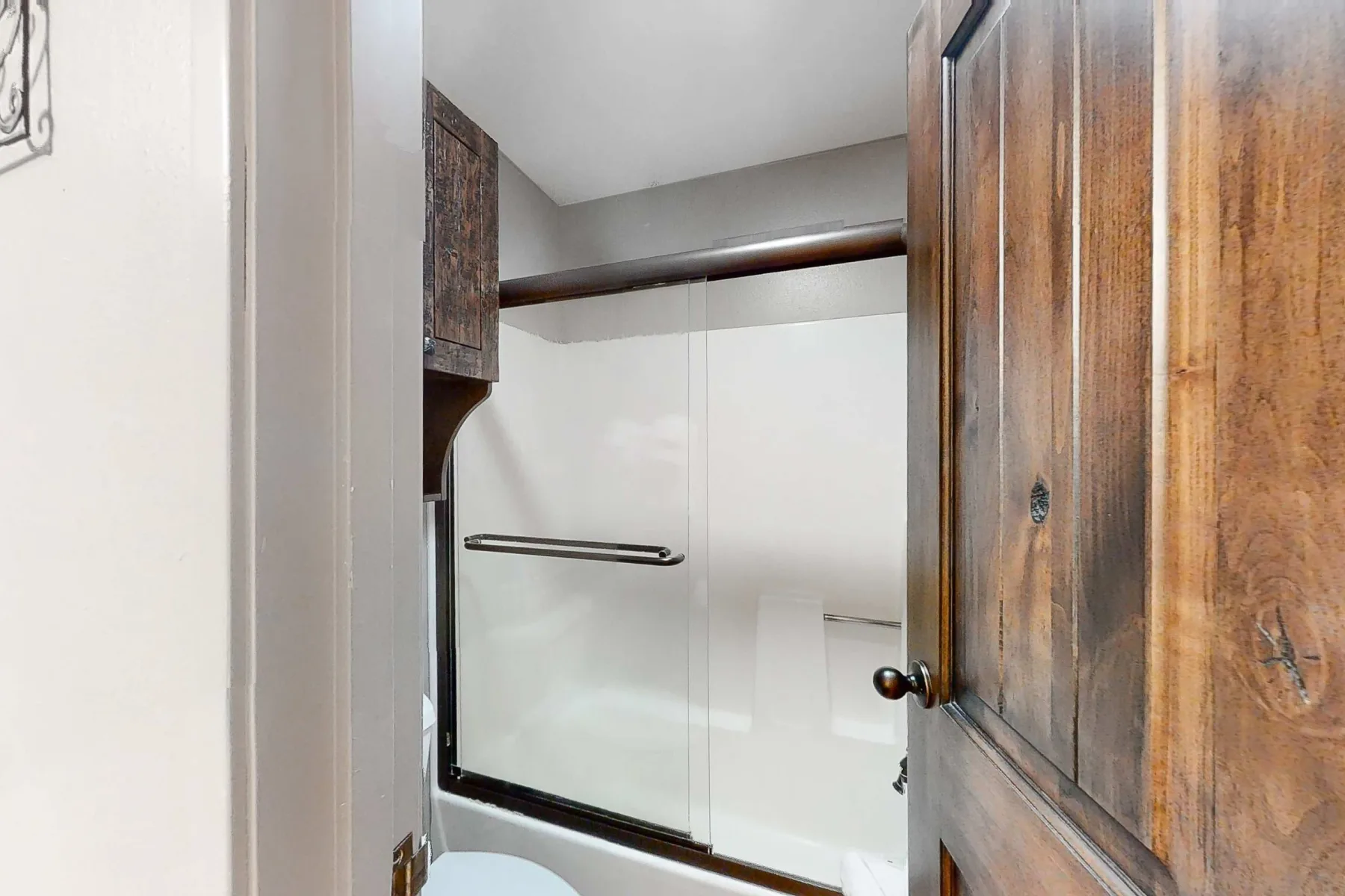 Un baño con una ducha de vidrio y gabinetes de madera.