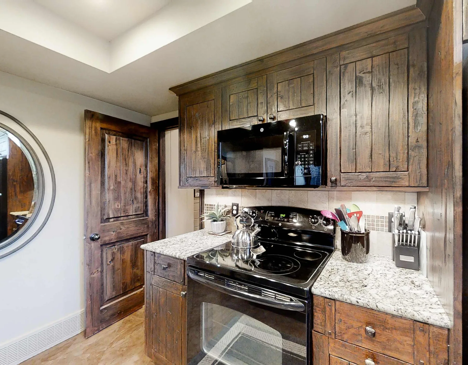 Una cocina con gabinetes de madera oscura, una estufa y un microondas empotrado.