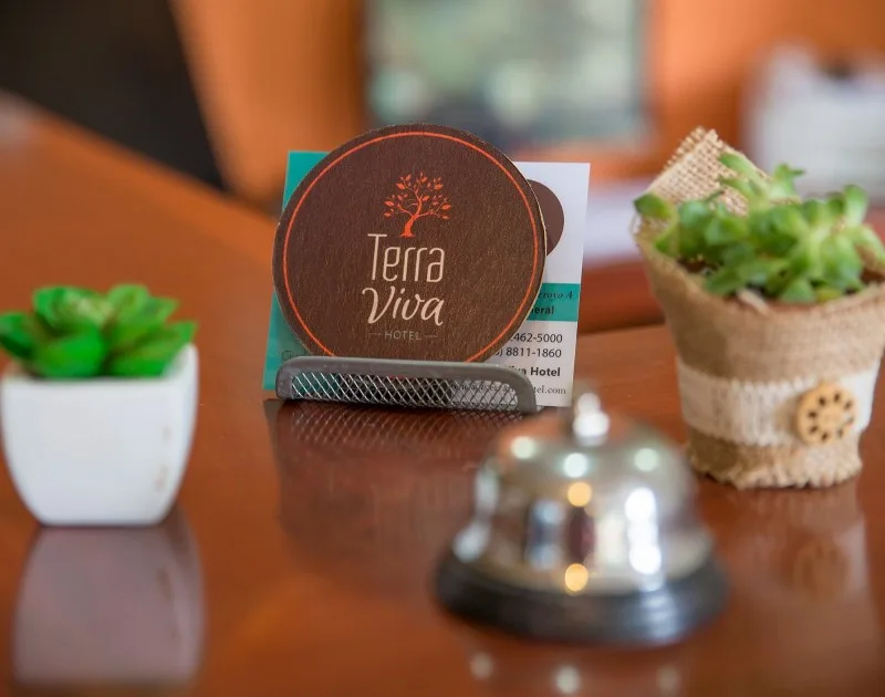 Representative hotel space: A hotel reception counter displays a sign beside small potted plants and a service bell.
