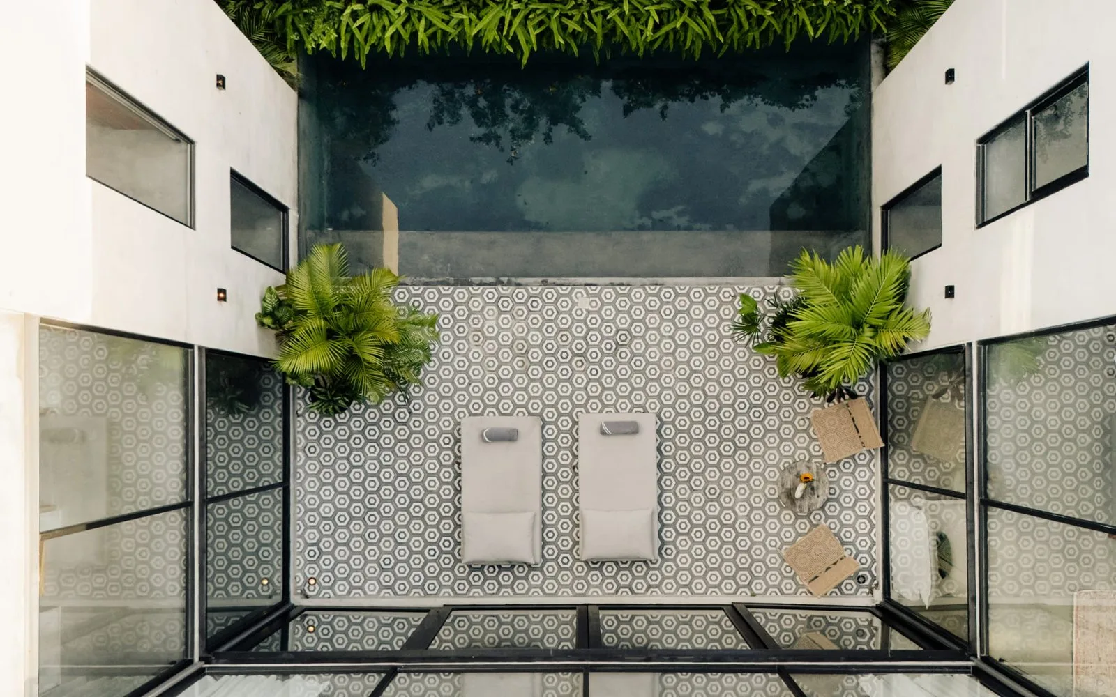 Un patio de azulejos con dos duchas en la pared y plantas frondosas.