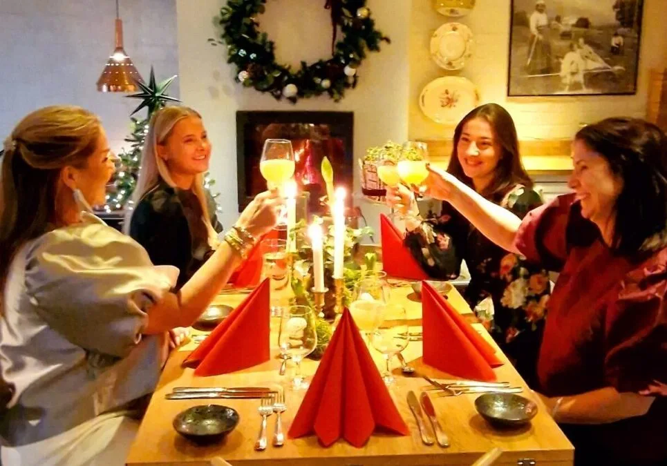 Representative hotel space: Women gather around a candlelit dining table, raising glasses in a toast.