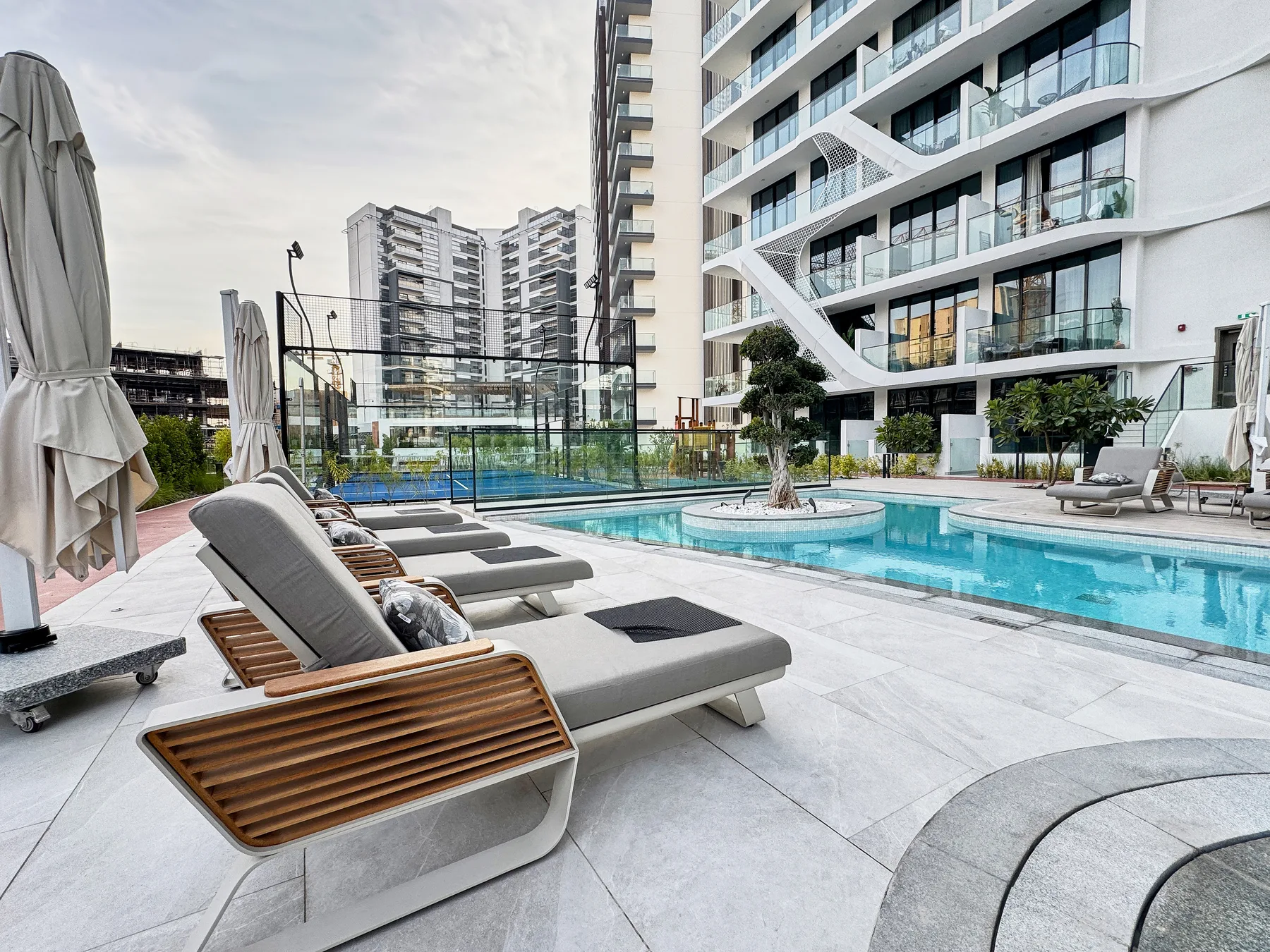 Shared amenity: An outdoor pool area with lounge seating beside a modern building.