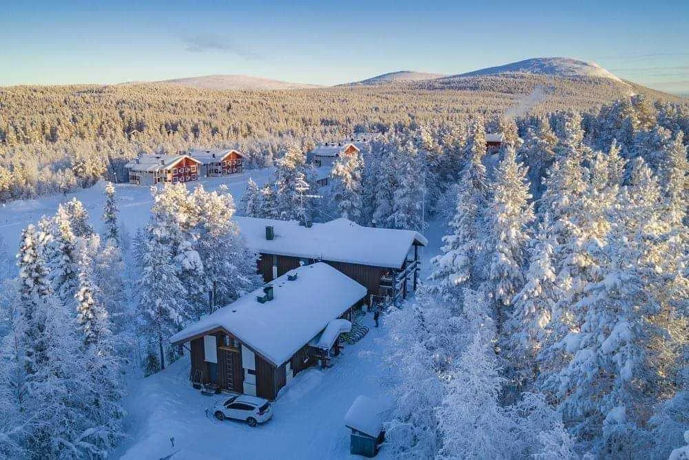 Representative hotel space: Snow-covered cabins sit among dense trees in a winter forest.
